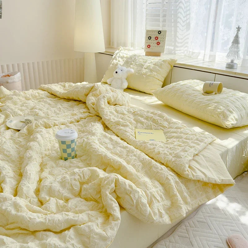 A fluffy yellow summer seersucker quilt comforter draped on a bed with a white lamp and window view.