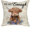 A decorative pillow cover featuring a print of a brown Highland cow with horns surrounded by wildflowers.