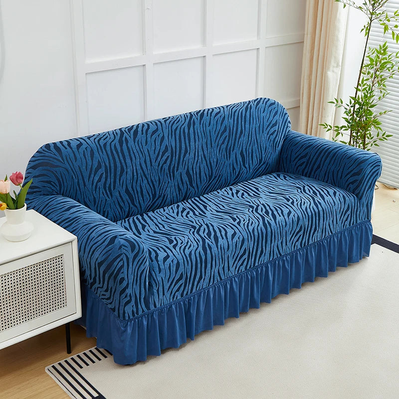 A deep blue anti-slip jacquard sofa slipcover is displayed on a light-colored floor in a bright room.