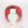 A ball of multi-colored wool yarn with shades of red and brown, labeled QJH Australiau waal 100% handarbeid.