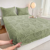A light green jacquard weave fitted sheet bedding spread on a white bed with a decorative pillow and a rabbit figurine nearby