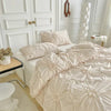 A luxurious beige pinch pleat duvet cover set displayed on a bed with white molding and sheer curtains.
