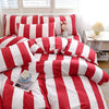 A red and white striped duvet cover set with pillows and a stuffed rabbit toy displayed on a bed.