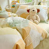 A duvet and pillow set featuring a yellow and white geometric pattern with a teddy bear decoration.