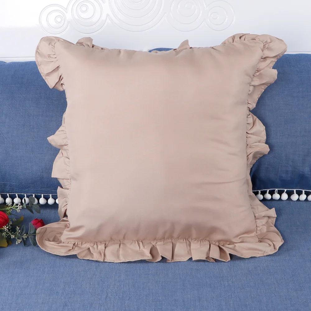A beige ruffled pillow cover displayed on a blue fabric background.
