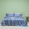 A light blue ice silk cooling quilt is displayed on a bed against a pale green wall.
