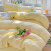 A yellow solid cotton bed linen set with pillows and a duvet, featuring a light green stuffed animal.