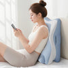 A woman is relaxing on a bed using a large blue and white memory foam body pillow while looking at her phone.