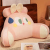 A pink cute animal plush sofa cushion with light beige accents resting on a wooden surface.