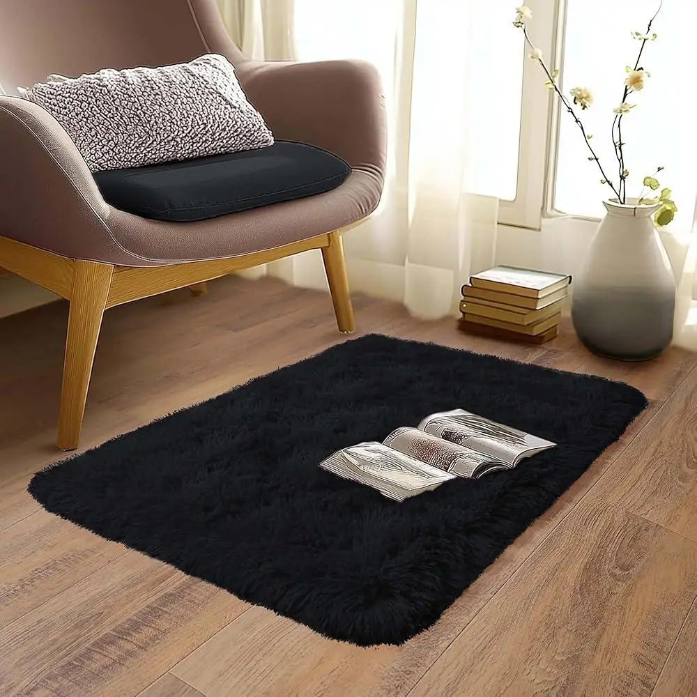 A plush solid black area rug placed on a wooden floor in a living room setting.