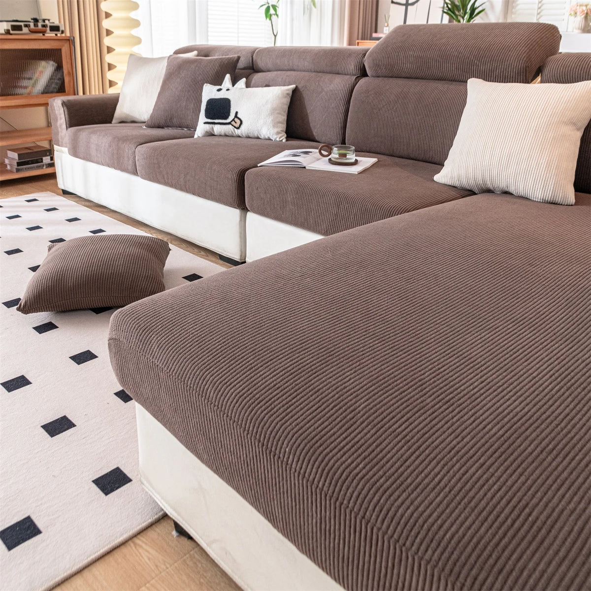 A brown removable jacquard seat cushion cover on a sofa with light beige pillows and a white rug.