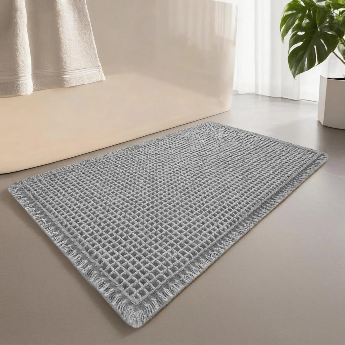 A gray waffle design non-slip bathroom mat placed on a light-colored floor next to a white sofa.