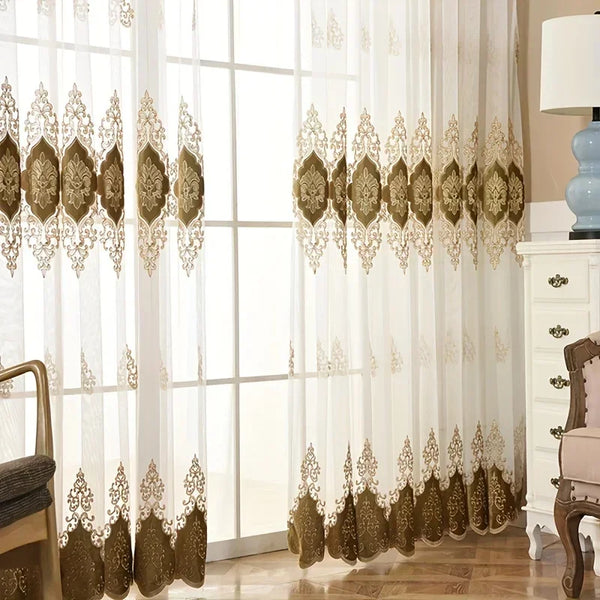 Gold embroidered gauze curtain with ornate detailing covering a large window.