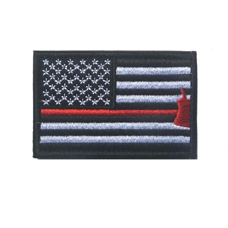 A black flag patch featuring the American flag design with a red hook attached to the hoist side.