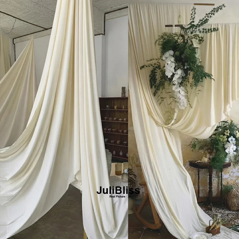 Cream draping stretch fabric used as a backdrop or curtain in an indoor setting.