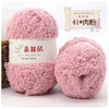 Pink fluffy velvet yarn in a cylindrical container with a wooden stick and small pink cactus for scale.