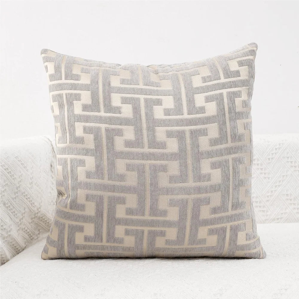 A beige and gray geometric jacquard lumbar pillow cover with a repeating maze pattern.