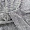 Close-up of a gray textured jacquard stretch sofa cover fabric with vertical ribbing.
