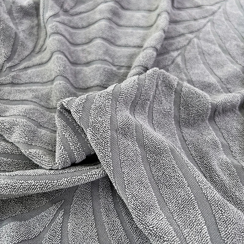 Close-up of a gray textured jacquard stretch sofa cover fabric with vertical ribbing.