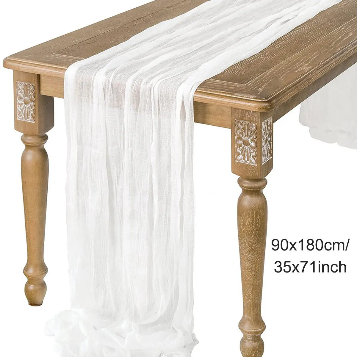 A white semi-sheer gauze table runner draped over a wooden table.