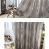 Gray sheer jacquard curtain panel draped in a window, featuring a subtle floral pattern.