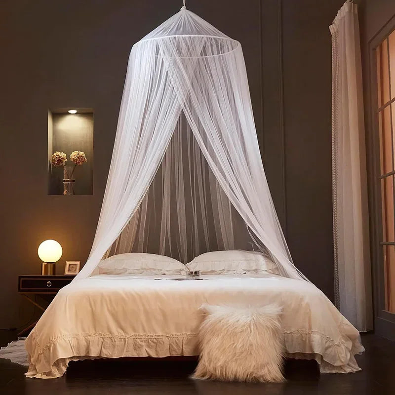 A sheer white dome mosquito net draped over a bed, creating a canopy effect in a dimly lit room.