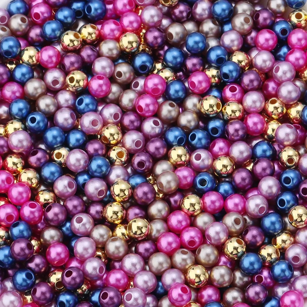 A close-up of many small, round imitation pearl beads in various shades of pink, purple, blue, and gold.