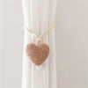 Cream colored plush heart tiebacks attached to a white curtain fabric.