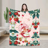 A woman holds up a pink strawberry shortcake plush throw blanket featuring strawberries and green foliage.
