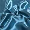 Close-up of a silky blue satin fabric draped and folded for a pillowcase.