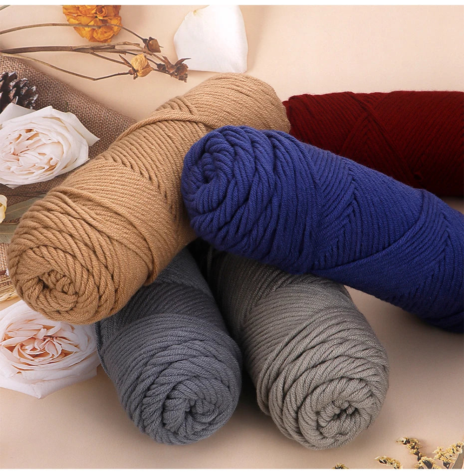A collection of hand-dyed yarn skeins in various shades of blue, gray, and tan stacked on a light background.