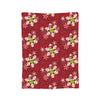 A red patterned throw blanket featuring white and lime green snowflake designs.