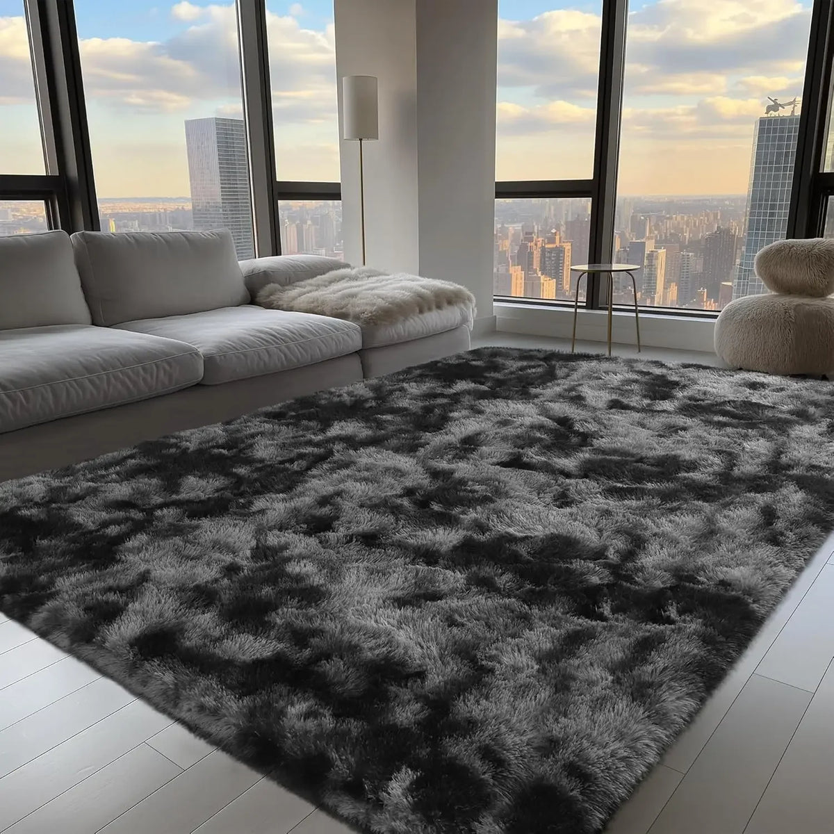 A dark gray and black faux fur rug covers the floor in a modern apartment with large windows overlooking a city skyline.