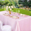 A pink satin tablecloth set for outdoor dining featuring gold plates, silverware, and clear glassware.