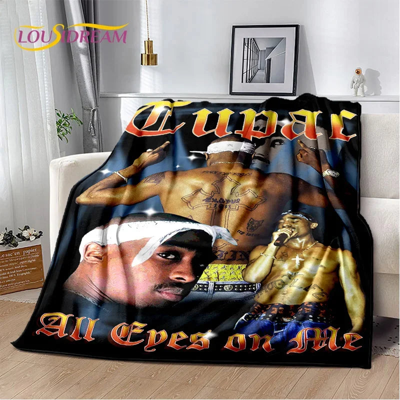 A black graphic throw blanket featuring a collage of portraits and text with an orange font.