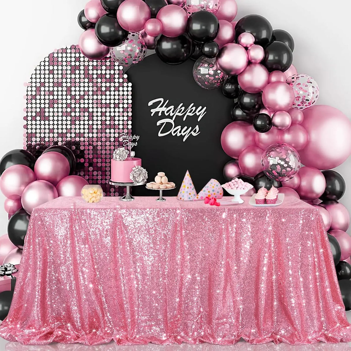 A pink sequin rectangle table cover is displayed with a backdrop of pink and black balloons and a chalkboard sign.