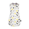 A white baby sleeping bag or swaddle featuring a pattern of various green and yellow leaves.