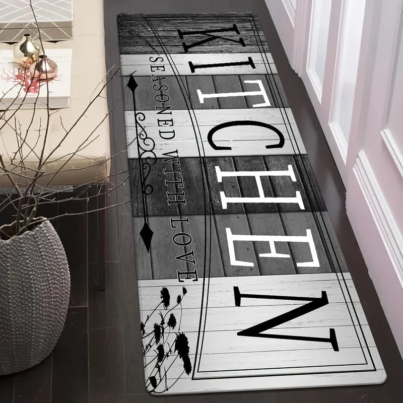 A long rectangular kitchen mat with black and white text featuring the word WITCHEN on a wooden background.