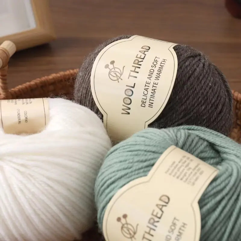 A ball of dark gray wool thread with a tag labeled Wool Thread Delicate and Soft Intimate Warmth