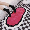 A pink and black cartoon decorative floor mat is placed on a black and white checkered floor.