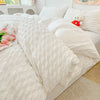 A white seersucker duvet cover and pillow set displayed on a bed with light-colored bedding.