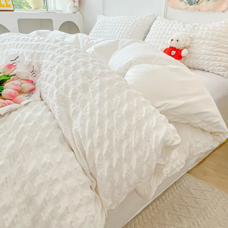 A white seersucker duvet cover and pillow set displayed on a bed with light-colored bedding.