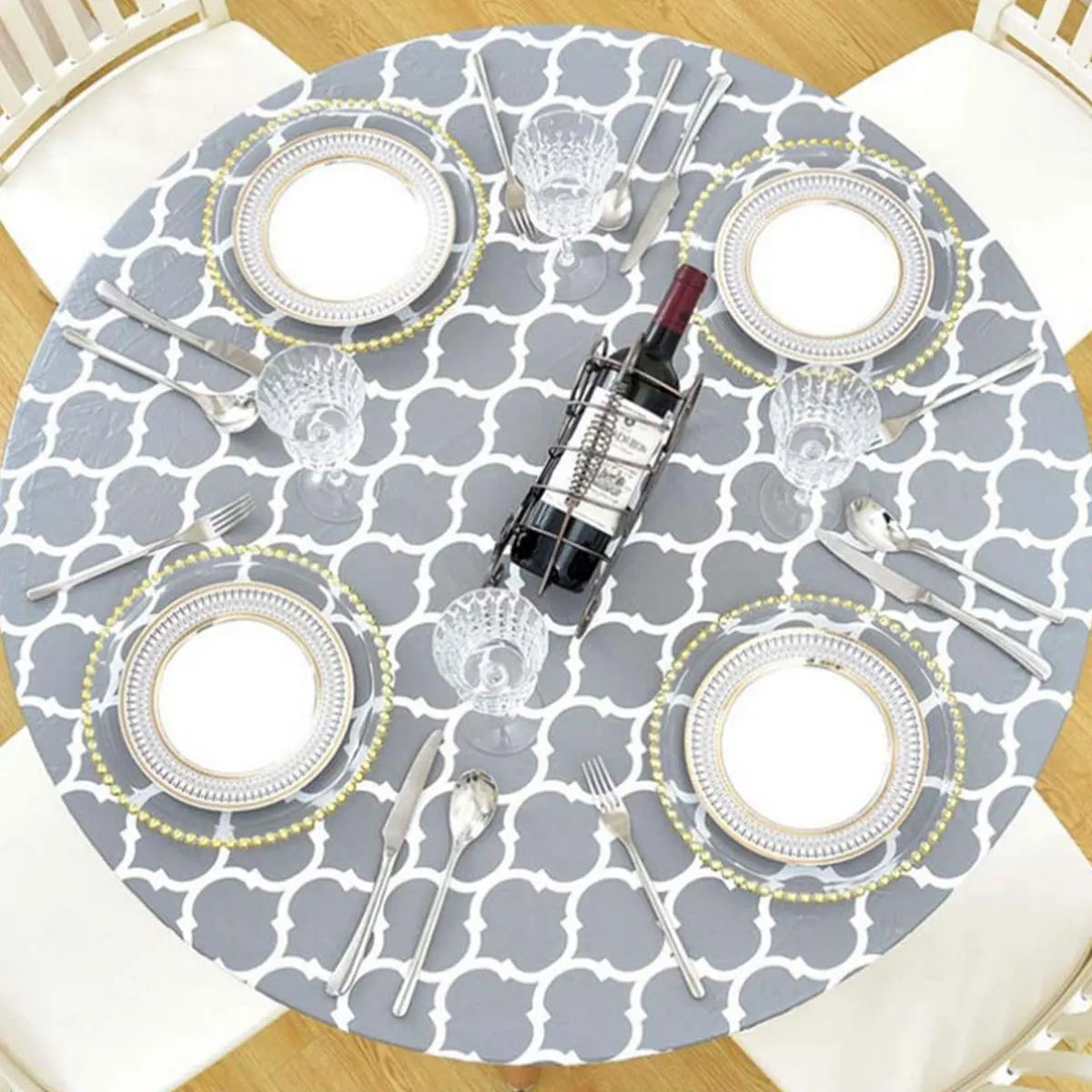A round gray vinyl tablecloth set for a meal featuring silverware and wine bottle.