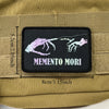 A black embroidered badge patch featuring stylized purple and white skeletal hands on a tan fabric background.