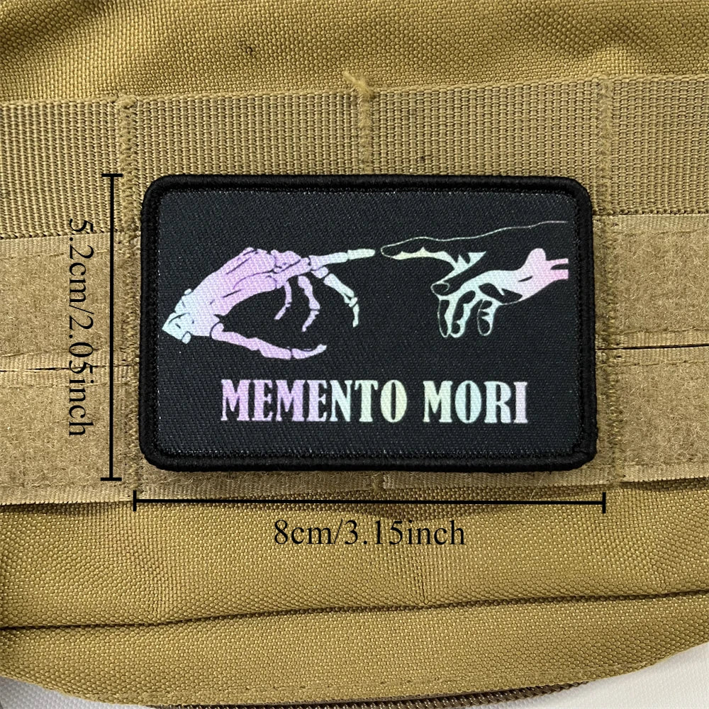 A black embroidered badge patch featuring stylized purple and white skeletal hands on a tan fabric background.