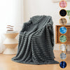 A dark gray soft flannel throw blanket draped on a light-colored sofa or chair.