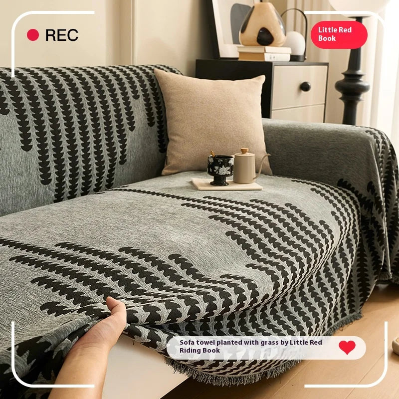 A gray sofa cover featuring a herringbone pattern with black and white accents, displayed on a wooden floor.