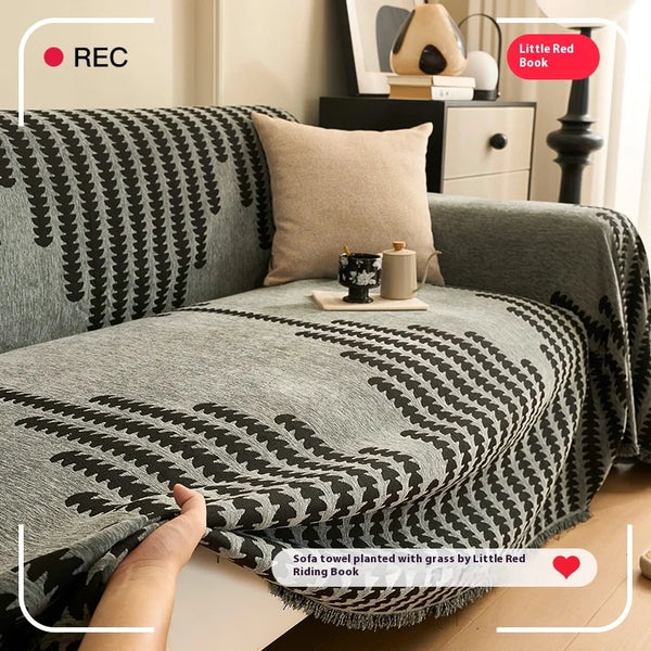 A gray sofa cover featuring a herringbone pattern with black and white accents, displayed on a wooden floor.