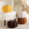 A collection of fluffy, round pumpkin plush decorations in yellow, white, and brown tones displayed on a light surface.