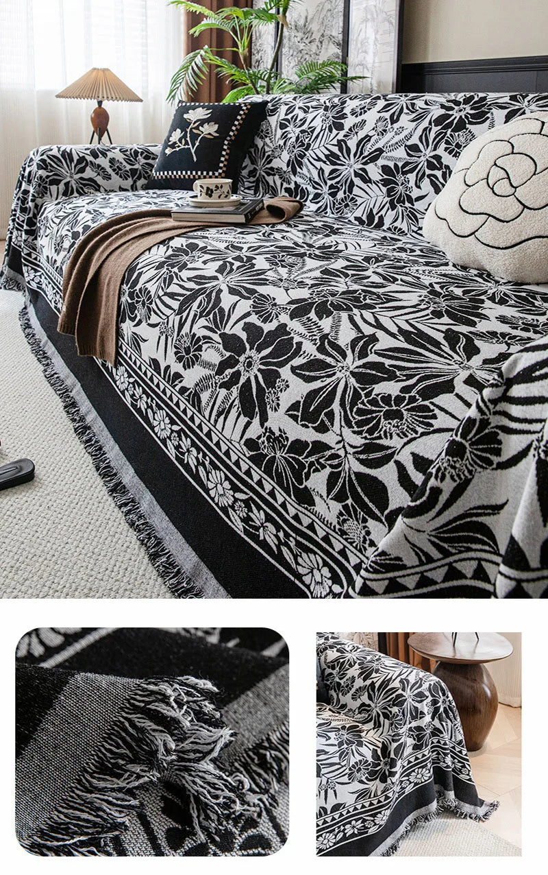 A black and white floral jacquard sofa throw blanket draped over a sofa, featuring intricate botanical patterns.